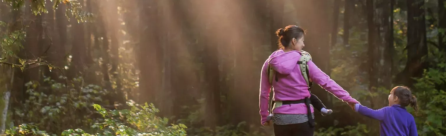Una mujer y una niña cogidas de la mano sonriendo y disfrutando de la naturaleza. 