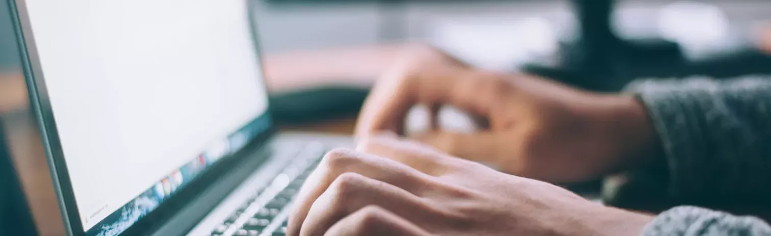 Manos utilizando el teclado de un ordenador portatil. 